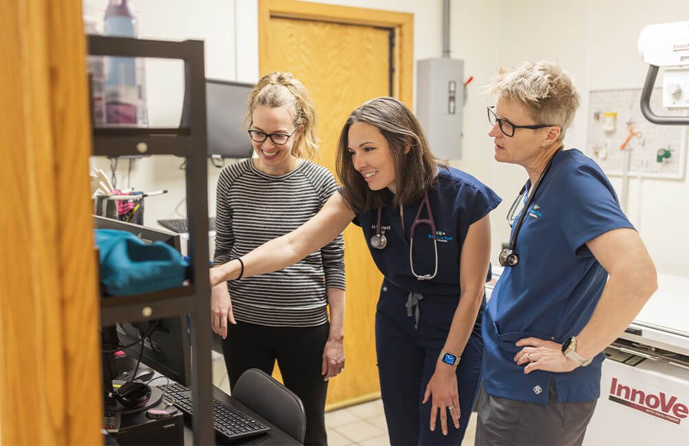 three female vet staff members looking at computer screen