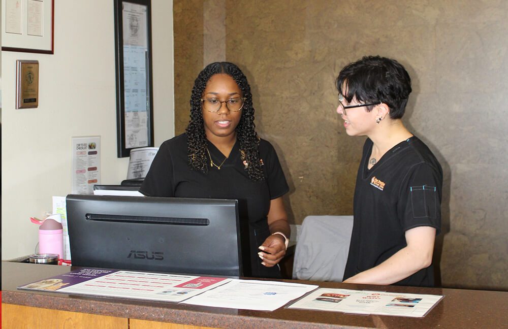 two vet staff members at the reception counter by computer